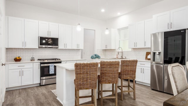 kitchen with white cabinets, light countertops, a sink, light wood-style floors, and appliances with stainless steel finishes