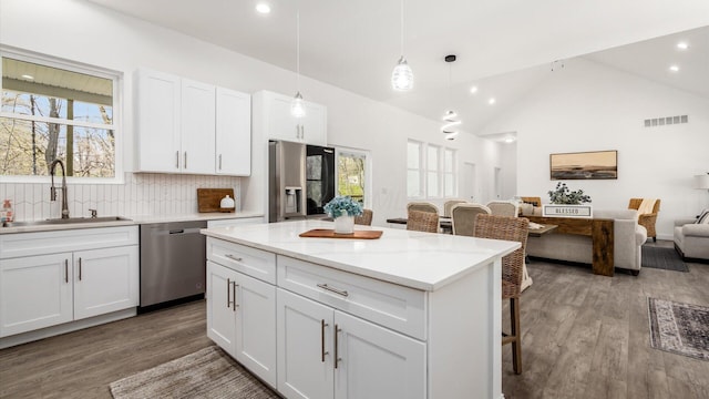kitchen with stainless steel appliances, visible vents, a sink, a kitchen bar, and open floor plan