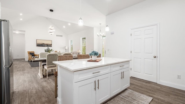 kitchen featuring a center island, freestanding refrigerator, white cabinetry, wood finished floors, and hanging light fixtures