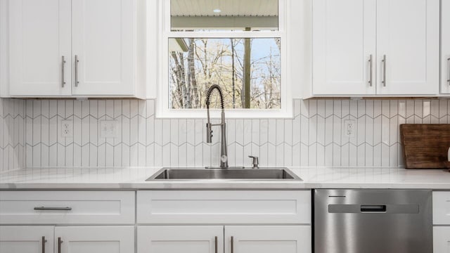 kitchen featuring light countertops, dishwasher, a sink, tasteful backsplash, and white cabinetry