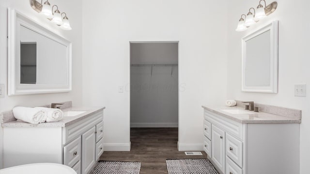 full bath with two vanities, wood finished floors, and a sink