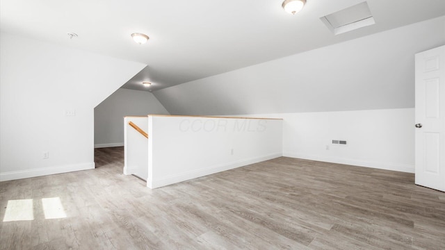 bonus room with vaulted ceiling, wood finished floors, attic access, baseboards, and visible vents