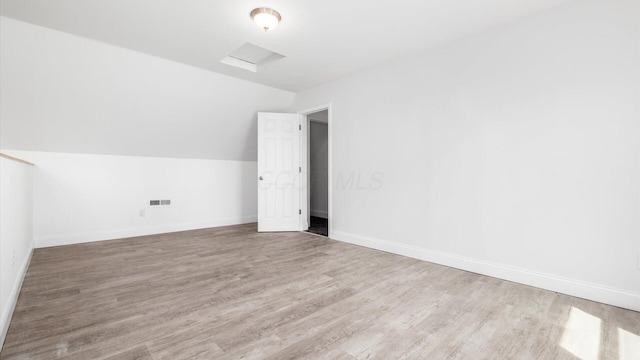 additional living space with vaulted ceiling, wood finished floors, visible vents, and baseboards