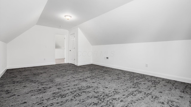 additional living space featuring lofted ceiling, baseboards, and dark carpet