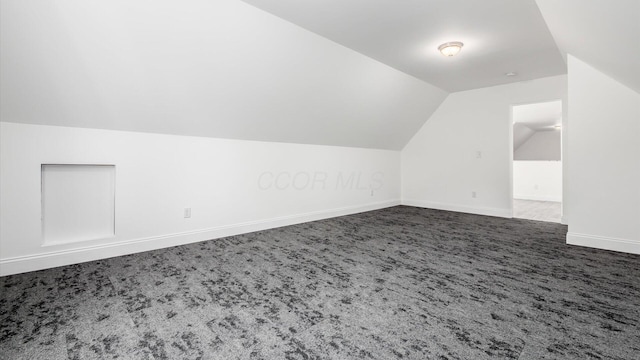 bonus room with dark carpet, lofted ceiling, and baseboards