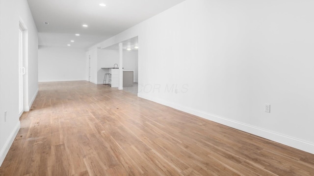 unfurnished living room featuring recessed lighting, light wood-style flooring, and baseboards