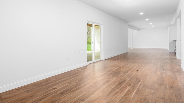spare room featuring light wood finished floors, baseboards, and recessed lighting