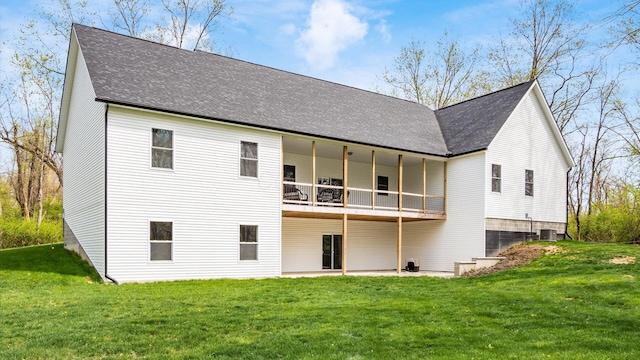 rear view of house with a shingled roof, a balcony, a yard, and central AC unit