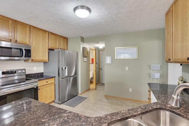 2131 Ripple Rd, Hilliard, OH 43026 - kitchen with a sink, appliances with stainless steel finishes, dark stone countertops, and a textured ceiling