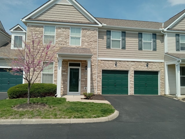view of front of property with driveway, stone siding, and a garage
