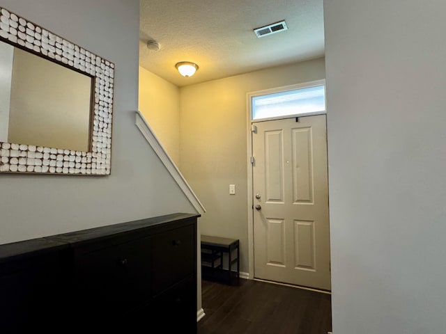 entrance foyer featuring dark wood finished floors, visible vents, a textured ceiling, and baseboards