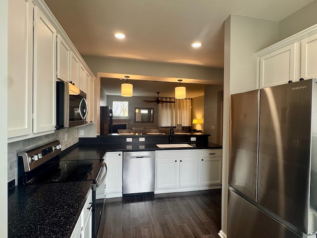 kitchen featuring dark countertops, a sink, a peninsula, and stainless steel appliances