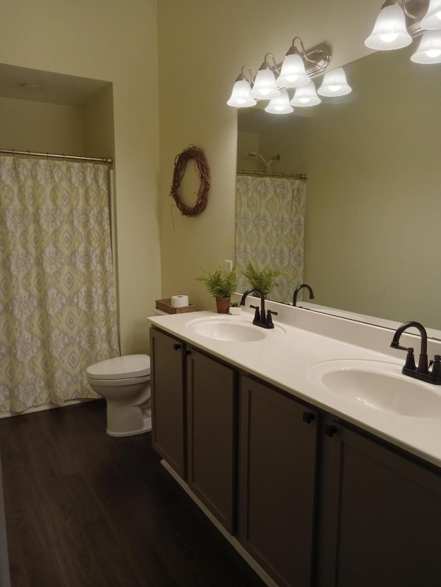 bathroom with toilet, double vanity, a sink, and wood finished floors