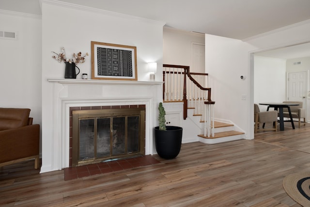 living room with visible vents, a tile fireplace, wood finished floors, and stairway