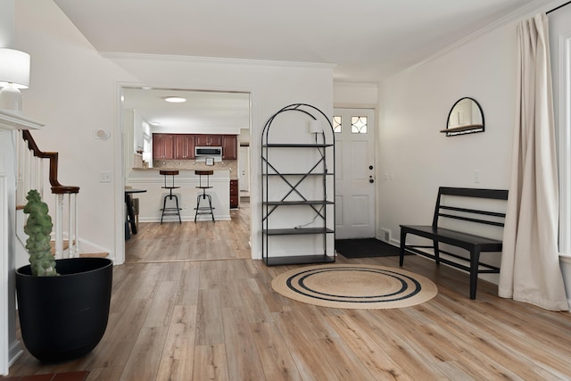 foyer entrance with visible vents, crown molding, and light wood finished floors