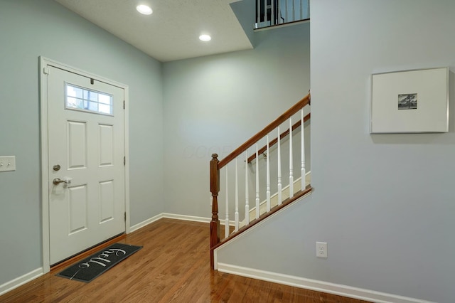 foyer entrance featuring recessed lighting, baseboards, stairs, and wood finished floors