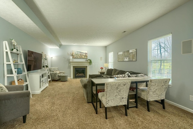 dining area with a glass covered fireplace, baseboards, carpet floors, and a textured ceiling