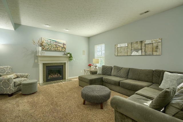 carpeted living room featuring visible vents, baseboards, a glass covered fireplace, and a textured ceiling