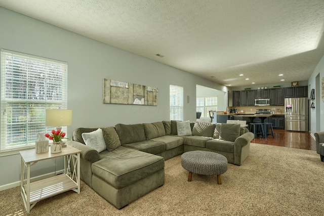 living area featuring dark carpet, visible vents, a textured ceiling, and recessed lighting