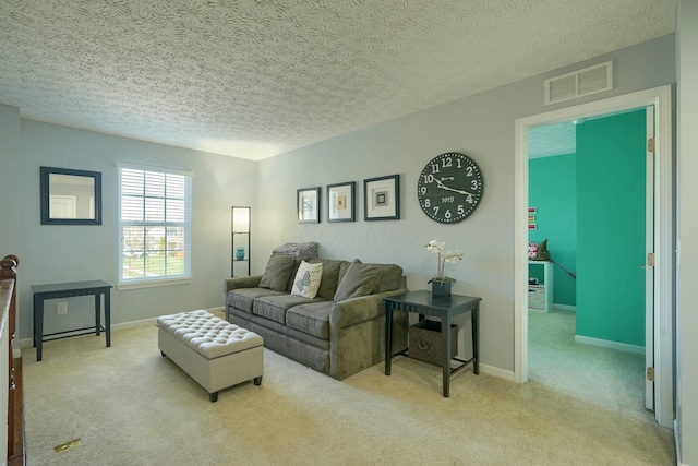 carpeted living room featuring baseboards, visible vents, and a textured ceiling