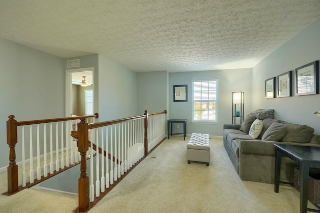 carpeted living area with baseboards, a textured ceiling, and visible vents