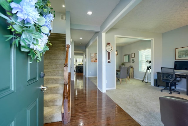 carpeted entrance foyer featuring recessed lighting, wood finished floors, visible vents, baseboards, and stairs