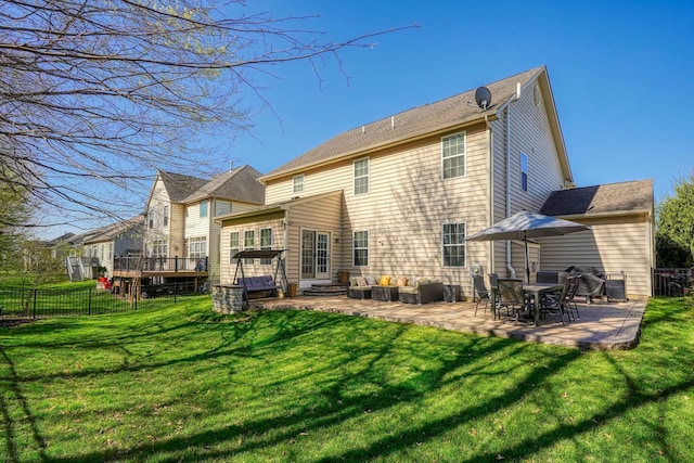 rear view of house with a wooden deck, a yard, a patio, and fence