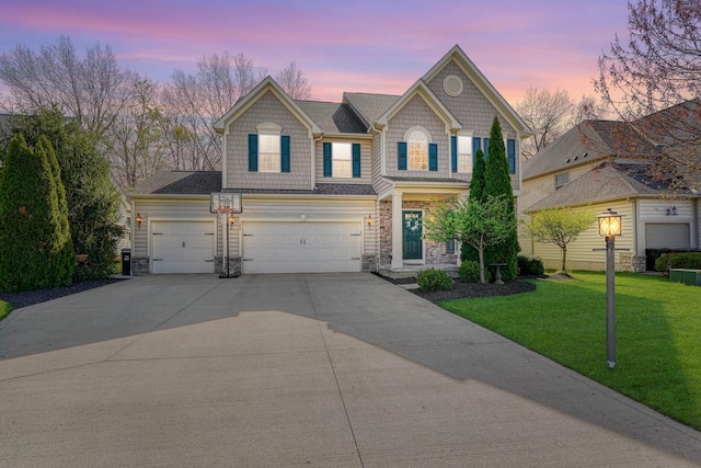 view of front facade with a garage, a yard, stone siding, and concrete driveway
