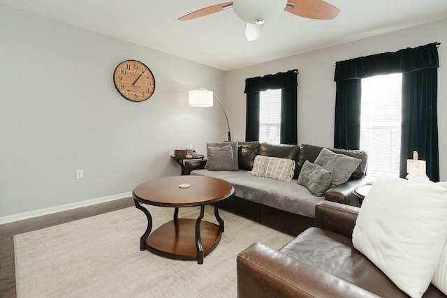 living room with ceiling fan, baseboards, and wood finished floors