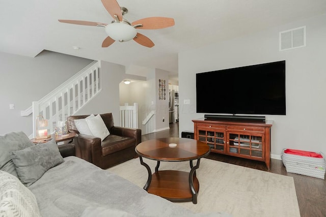 living area featuring wood finished floors, visible vents, a ceiling fan, and baseboards