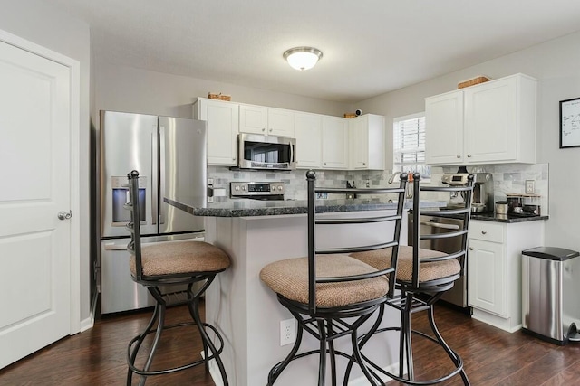kitchen with backsplash, appliances with stainless steel finishes, a kitchen breakfast bar, and white cabinetry