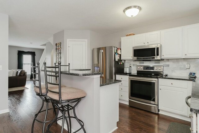 kitchen with white cabinets, backsplash, dark wood-style flooring, and stainless steel appliances