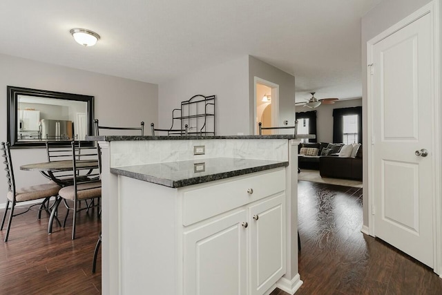 kitchen featuring dark wood-type flooring, freestanding refrigerator, white cabinetry, and ceiling fan