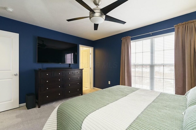 bedroom with ceiling fan, light carpet, and baseboards