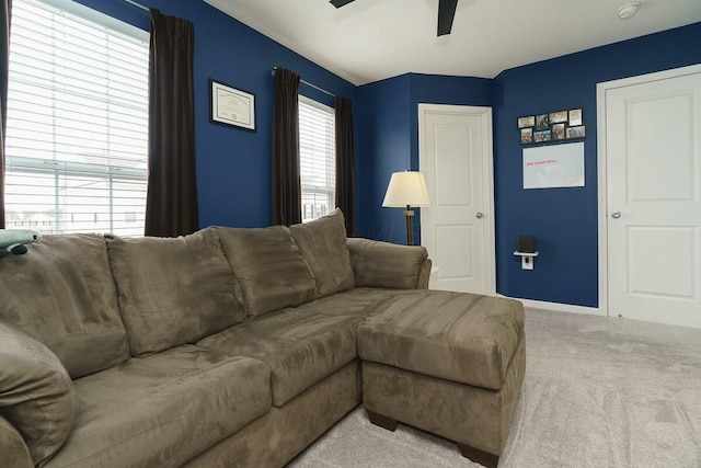 carpeted living room featuring baseboards and ceiling fan