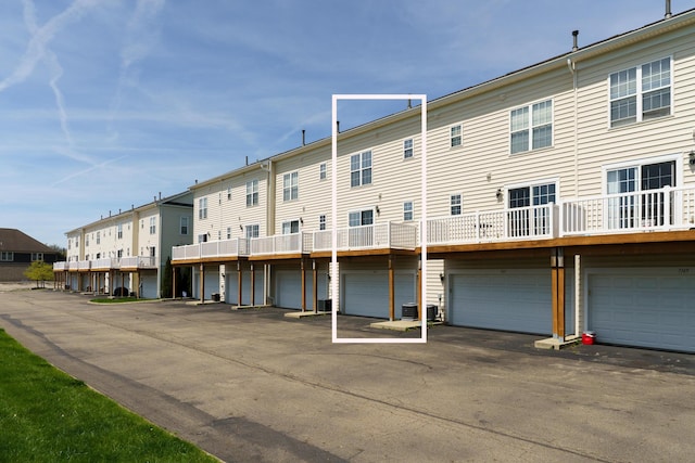 rear view of house featuring a residential view, central air condition unit, and an attached garage
