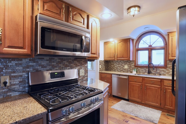 536 E Allen St, Lancaster, OH 43130 - kitchen with backsplash, appliances with stainless steel finishes, light stone countertops, a sink, and light wood-style floors