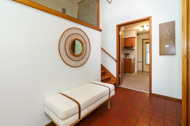 hall featuring stairway, dark tile patterned floors, and baseboards