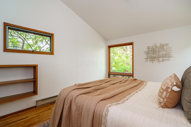 bedroom featuring lofted ceiling, wood finished floors, and a baseboard heating unit