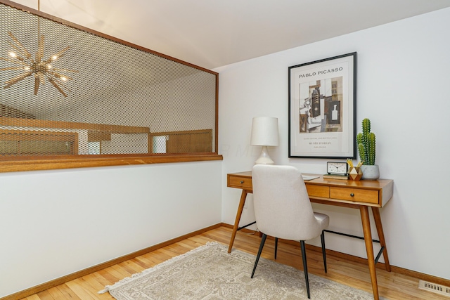 home office with wood finished floors, visible vents, and baseboards