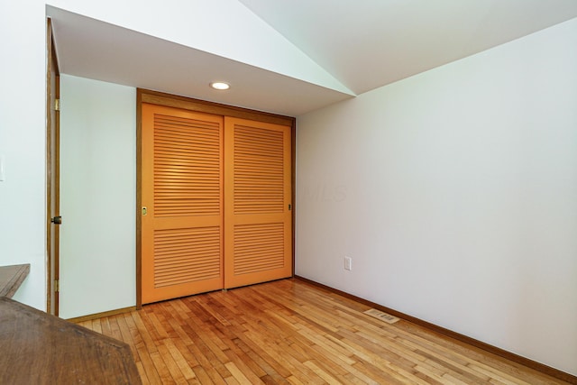 unfurnished bedroom featuring a closet, visible vents, lofted ceiling, and light wood-type flooring