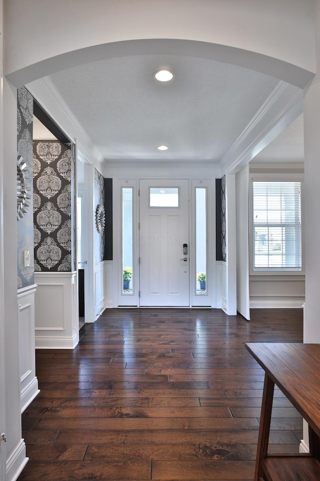 entryway with crown molding, hardwood / wood-style floors, and a decorative wall