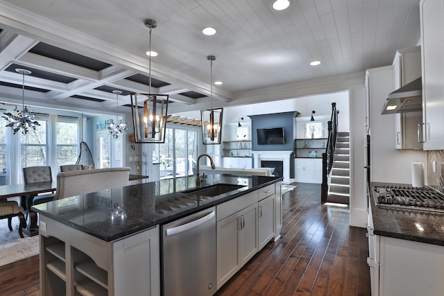 kitchen with a sink, appliances with stainless steel finishes, open floor plan, a fireplace, and a notable chandelier