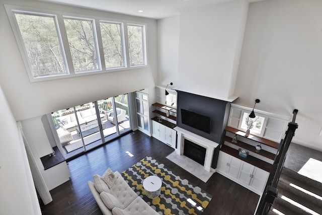 living room with wood finished floors, a high ceiling, and a fireplace with flush hearth