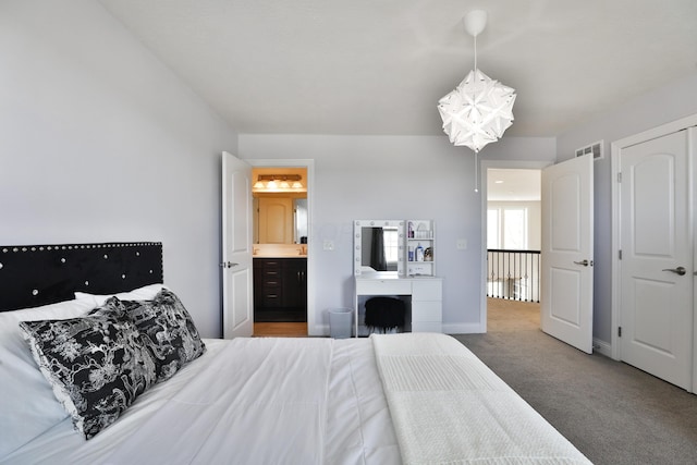 bedroom with ensuite bath, carpet, baseboards, visible vents, and a notable chandelier