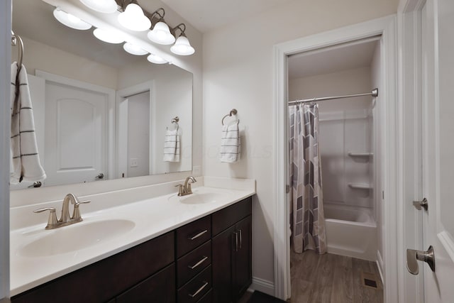 full bathroom with shower / bathtub combination with curtain, wood finished floors, double vanity, and a sink