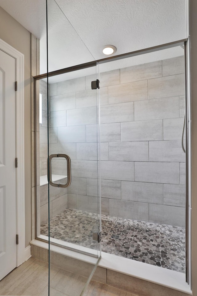 bathroom featuring a textured ceiling, recessed lighting, and a stall shower