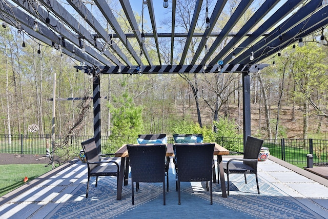 view of patio / terrace with fence, outdoor dining area, a forest view, and a pergola