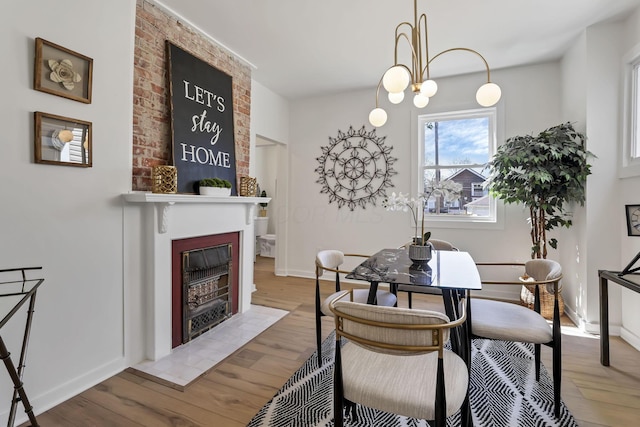 1719 Oak St, Columbus, OH 43205 - dining space with baseboards, wood finished floors, a large fireplace, and a notable chandelier