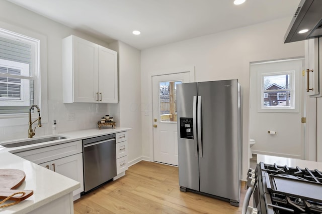 1719 Oak St, Columbus, OH 43205 - kitchen featuring light wood finished floors, stainless steel appliances, extractor fan, a sink, and white cabinetry